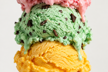 Three-scoop ice cream cone with strawberry, mint chocolate chip, and mango ice cream.