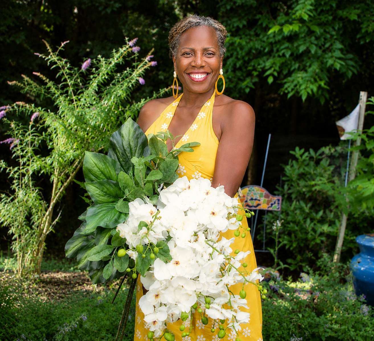 Woman in yellow sundress holding flowers in the garden
